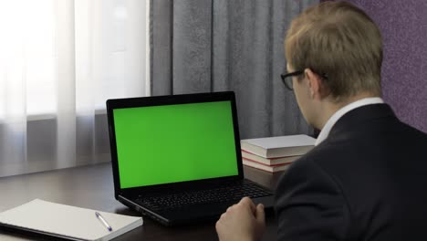 hombre tiene videoconferencia de llamada en portátil con pantalla verde. trabajo a distancia en línea