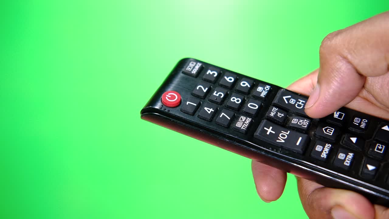 녹색 스크린 을 향해 tv 리모컨 을 들고 있는 남자 의 손
