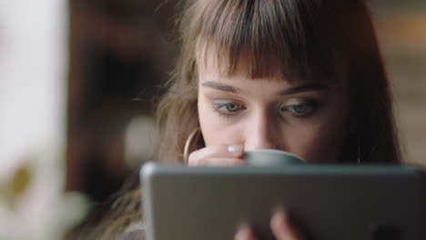 cerca hermosa joven caucásica estudiante usando una tableta en un café bebiendo café navegando en línea leyendo mensajes de redes sociales disfrutando de compartir un estilo de vida relajante