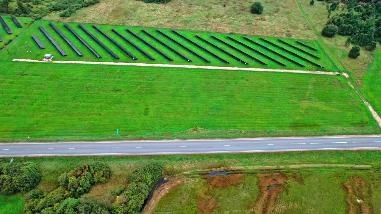 Solar panels line green fields in Latvia near a winding road