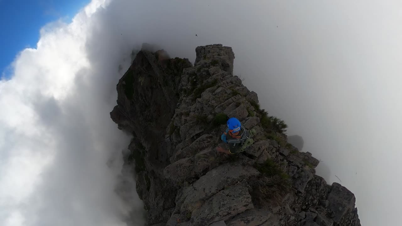 toma amplia de 360 pov de un hombre joven, en forma y fuerte que sube cuidadosamente a la cima del pico das torres en madeira