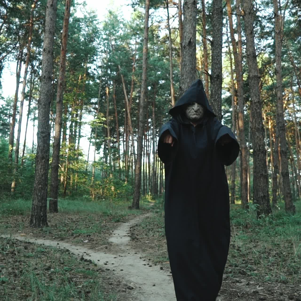 Evil ghost hooded creature walking across forest. Halloween