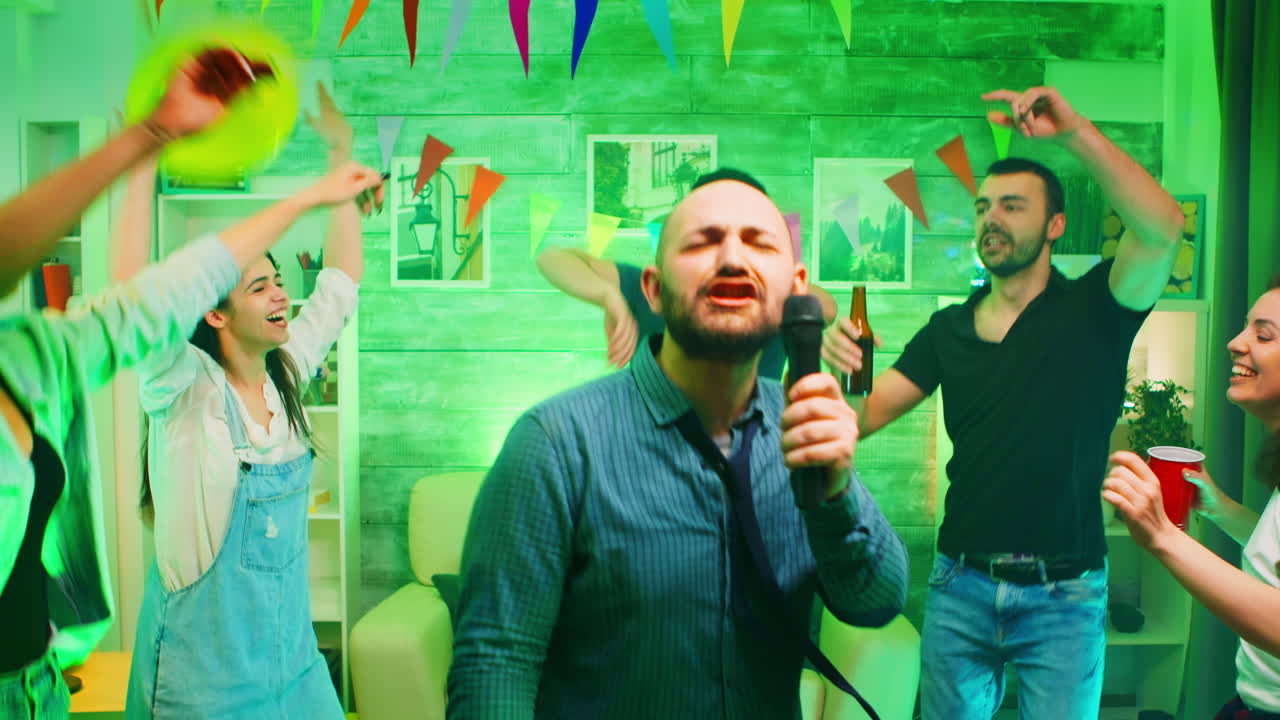 Uomo calvo attraente che fa karaoke a una festa scatenata con luci al neon.