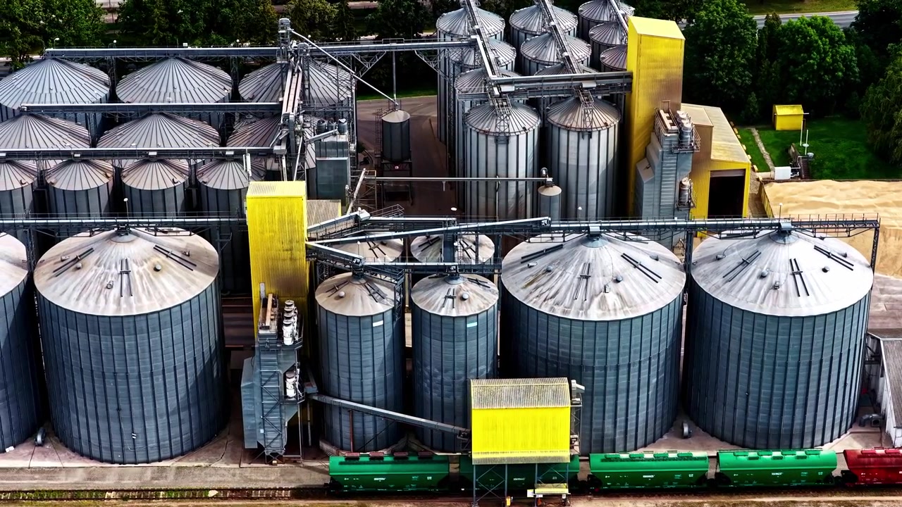 Draufsicht auf industrielle Getreidesilos und Güterwaggons.