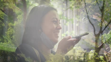 animation of happy mixed race woman using smartphone over landscape