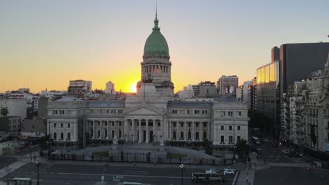 aerial jib down of argentine congress palace surrounded by buildings at golden hour in busy buenos aires