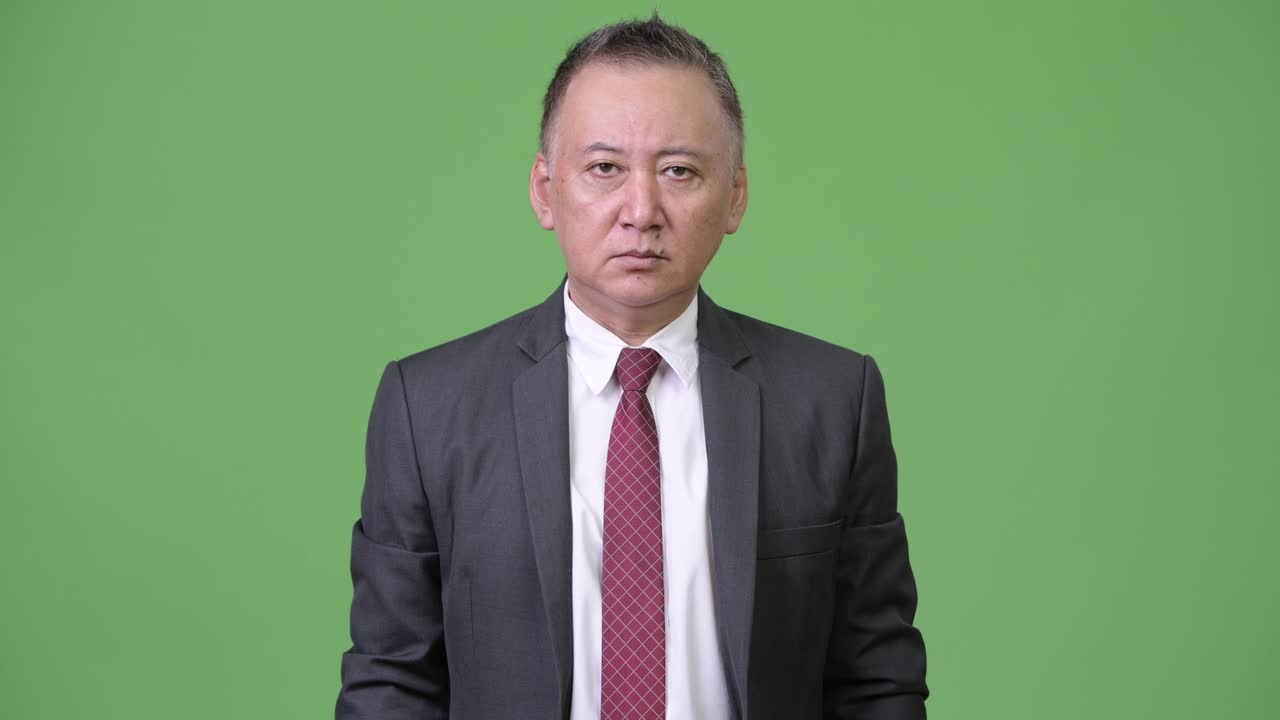 시끄러운 소음으로부터 귀를 고 있는 성숙한 일본인 사업가