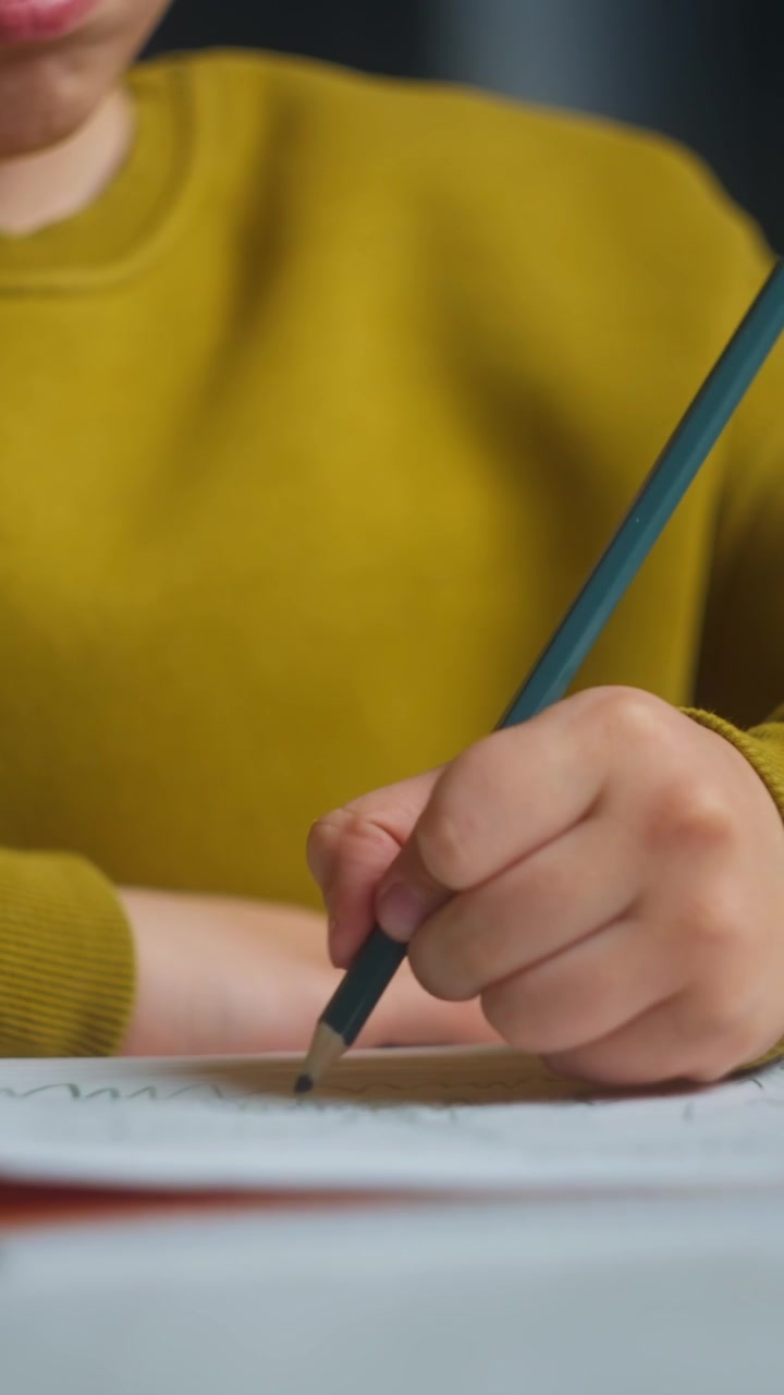 Primo piano di un bambino che disegna su un quaderno con una matita