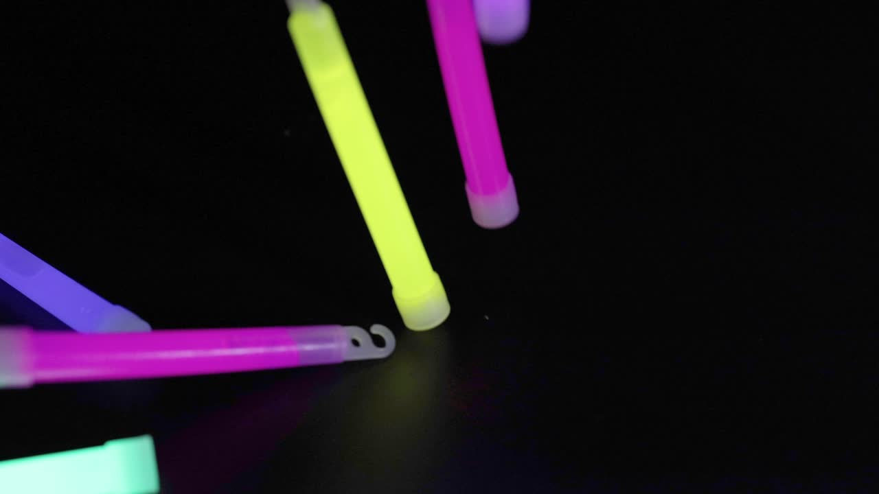 Glow sticks falling and landing on dark surface