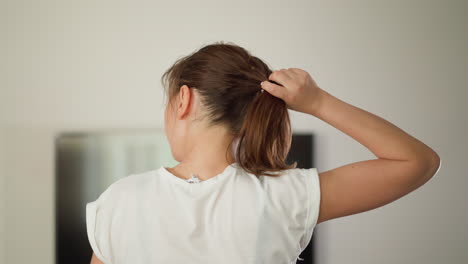 mujer corriendo tira el cabello en casa. mujer deportiva en camiseta blanca corre con el cabello suelto en el gimnasio doméstico. ejercicio para el bienestar