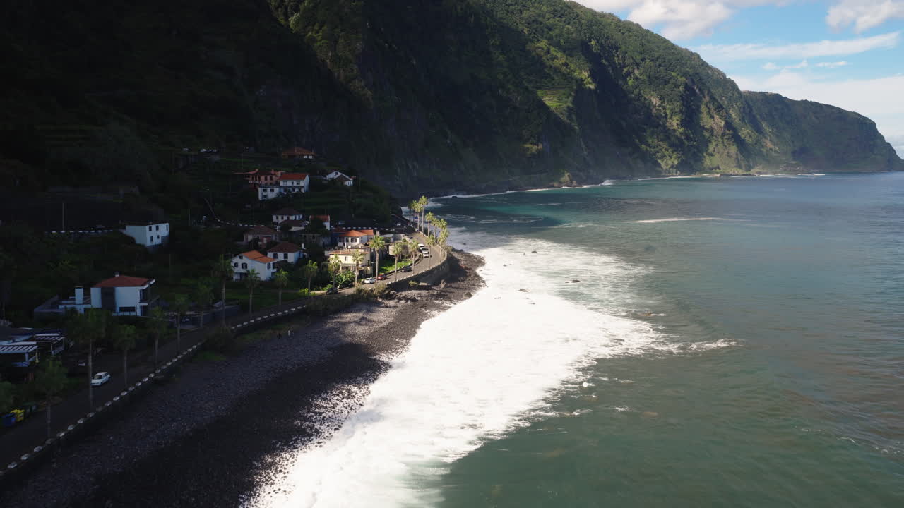 Vista aerea panoramica di onde marine e un villaggio costiero tra verdi montagne