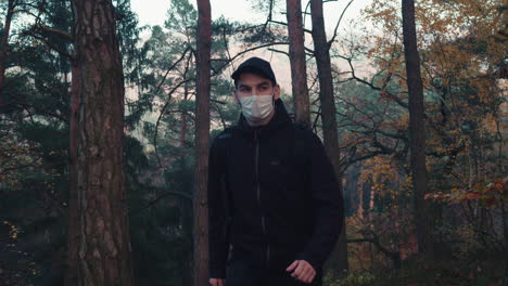 caucasian man walking in forest with medical face mask, life after covid pandemic, middle shot side view