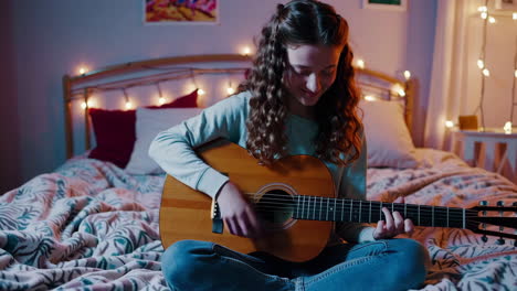 young woman playing acoustic guitar in a cozy bedroom