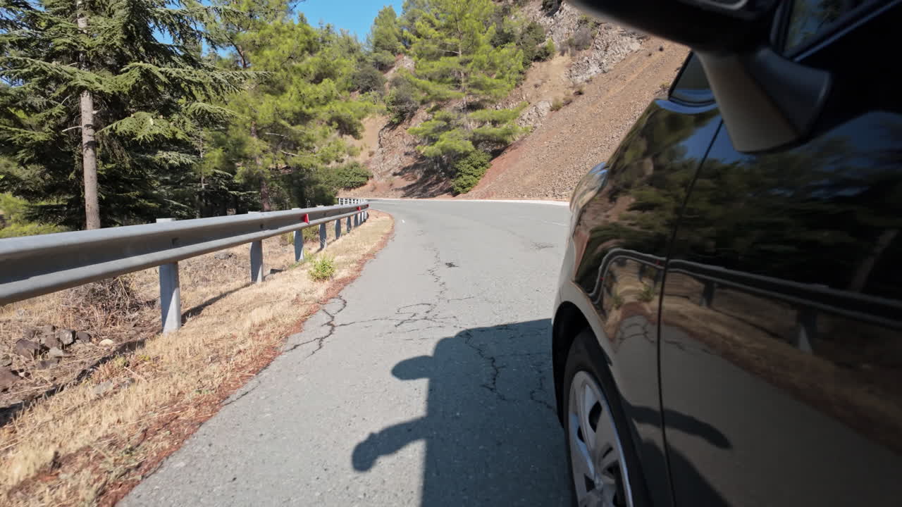 Car driving on a sunny road with a close-up of the side and wheel casting a shadow