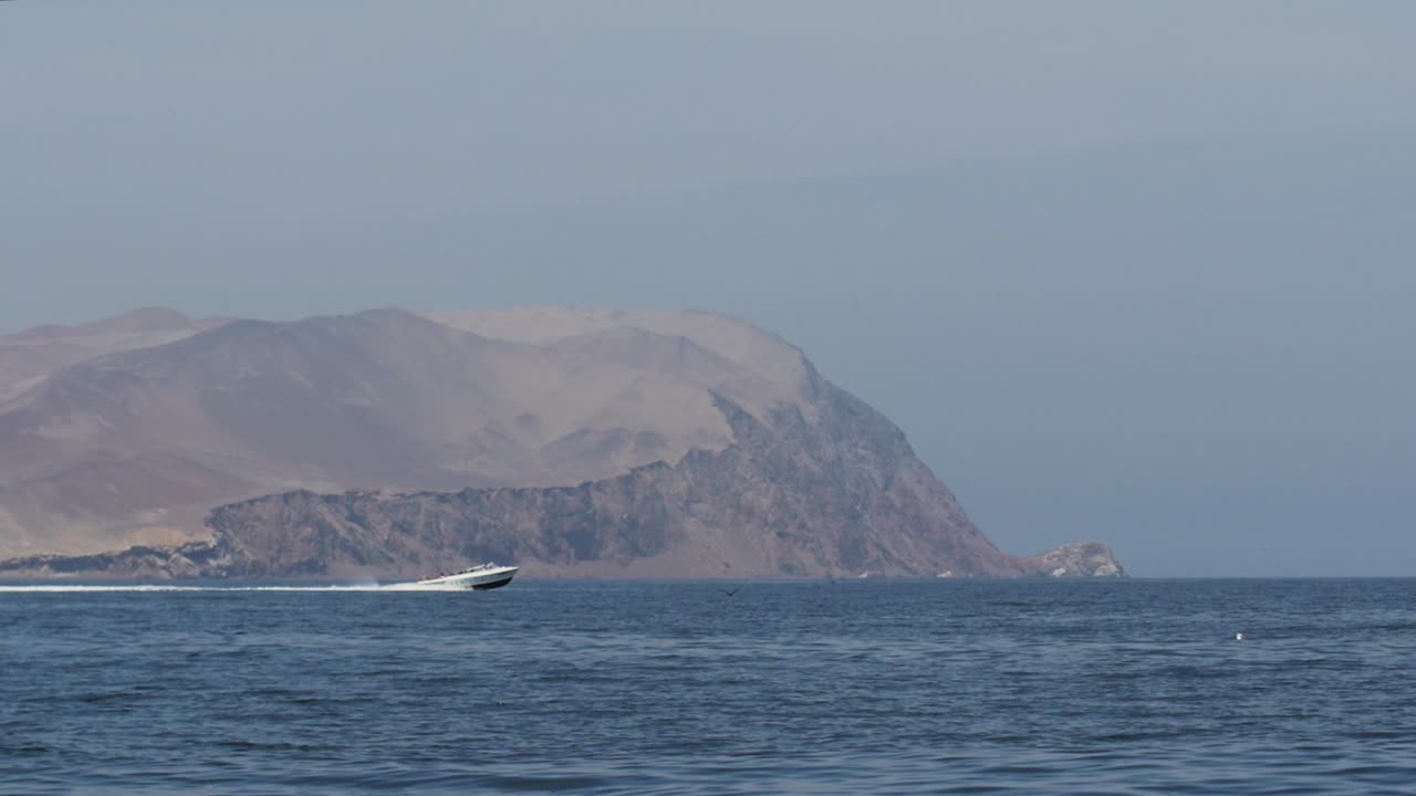 Motor boat sailing with mountain in background near Paracas Peru