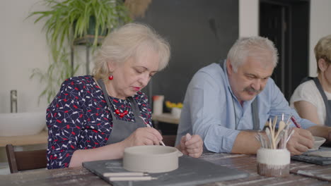 Three-elderly-people-work-on-a-potter's-wheel-in-slow-motion