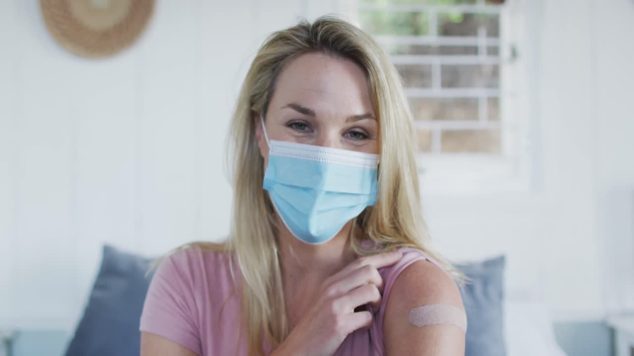 Felice donna matura caucasica che mostra il cerotto sul braccio dove è stata vaccinata contro il coronavirus