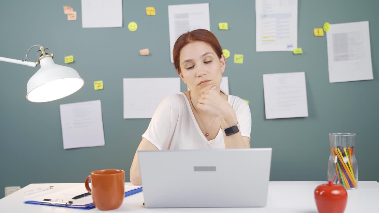 Woman looking at laptop is thoughtful.
