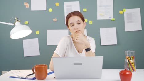 woman looking at laptop is thoughtful.