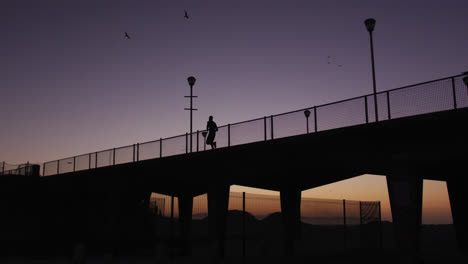 silueta de un hombre corriendo por el puente por la noche