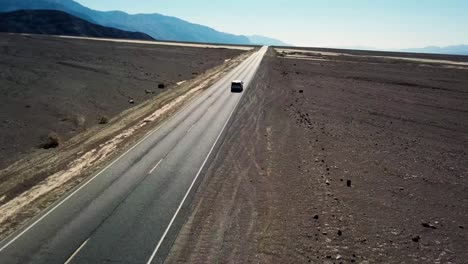 tomada aérea de un avión no tripulado de un coche que conduce a través del valle de la muerte en california en estados unidos
