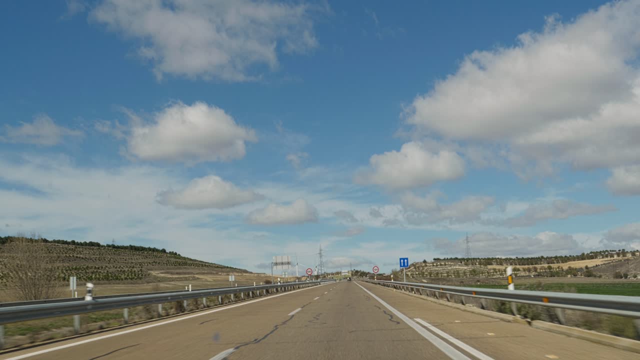 Guida su una strada di campagna sotto un cielo azzurro con nuvole