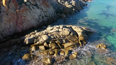 aerial shot of rocks in clear turquoise water in front of su giudeu beach in south sardinia, italy