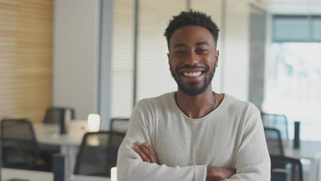 portrait of young businessman standing in modern open plan office