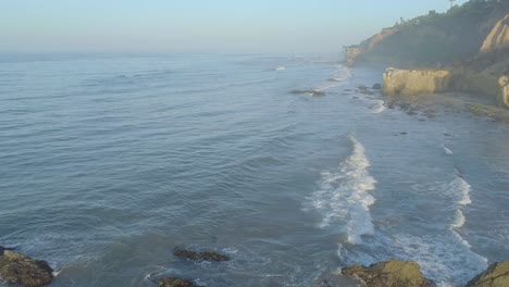 Aerial-shots-of-El-Matador-beach-over-breaking-waves-and-rocks-on-a-hazy-summer-morning-in-Malibu,-California