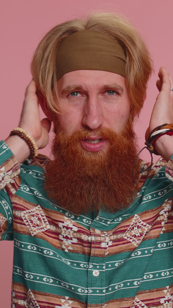 Uomo hippie irritato che si copre le orecchie, che fa gesti, che non evita i consigli, che ignora i rumori spiacevoli, che parla forte.