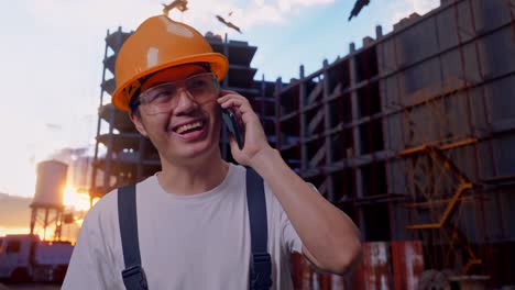 un trabajador asiático hablando en su teléfono inteligente y mirando a su alrededor en el sitio de construcción