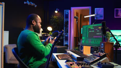 productor creando una pista tocando la guitarra acústica en el estudio casero