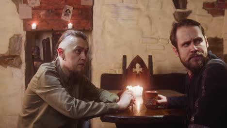 two men enjoying drinks in a medieval tavern