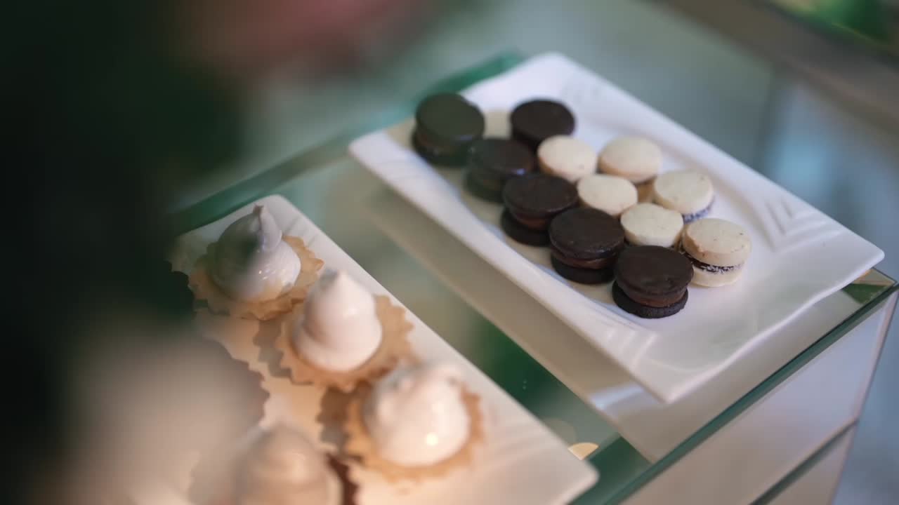 Sweet table display with gourmet desserts arranged neatly for elegant celebration or reception, white and black pudding and macaroons