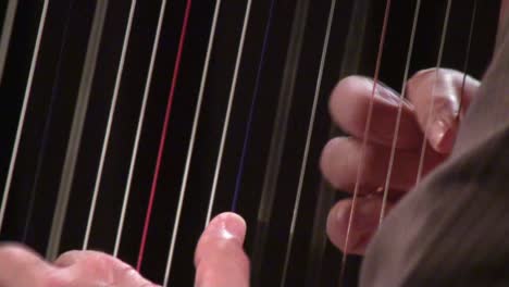 close up of hands playing the harp and plucking strings with a blurred background