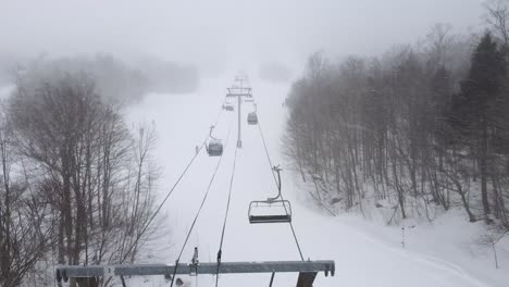 drone rises above ski lift chairs in snowy weather at resort in orford, quebec, canada