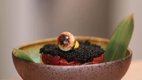 plating delicious raw tuna topped with black sushi caviar using a stainless steel food ring mold - close up