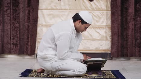 hombre musulmán leyendo el libro del corán en casa en la india