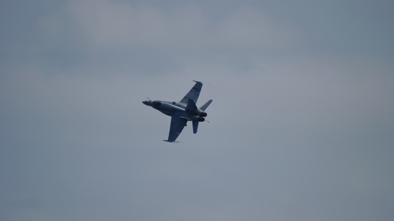 Fighter jet with landing gear extended executes a series of aerobatic maneuvers, showcasing agility and precision against a backdrop of clouds