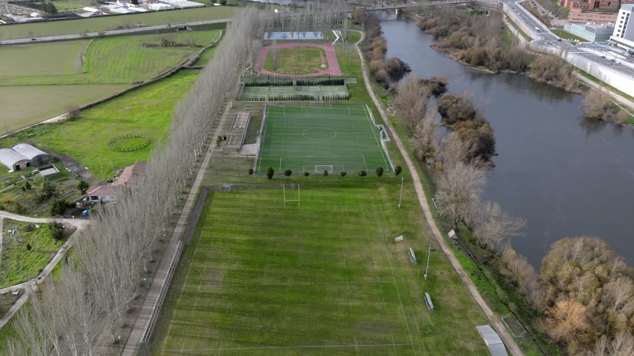 полет над футбольным полем и беговыми дорожками у голубой реки в испании