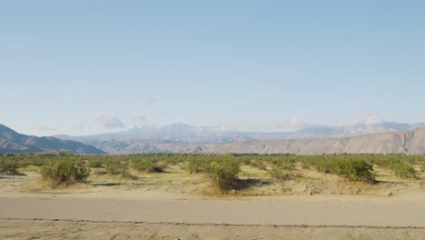 Schwenkaufnahme-Einer-Unbefestigten-Straße,-Umgeben-Von-Atemberaubenden-Bergen-In-Der-Anza-Borrego-Wüste