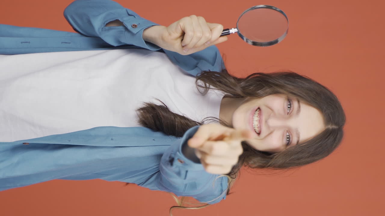 video vertical de una mujer joven mirando a la cámara con lupa.