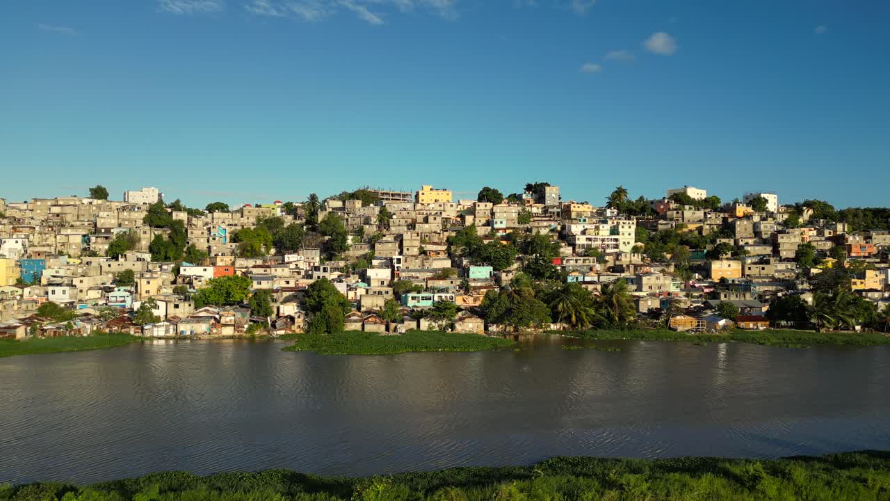 Cinematic aerial of La Zurza, Santo Domingo — raw urban density along the Ozama River. Perfect for documentaries, news, and social impact. Lateral drone shot with space for text