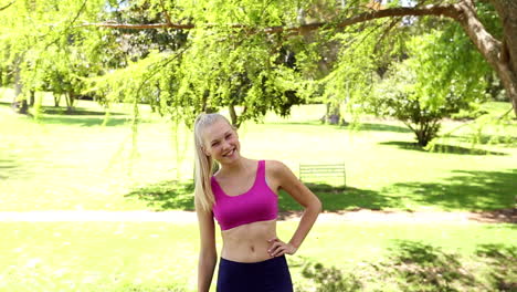 Fit-Blondine-Springt-Und-Lächelt-In-Die-Kamera-Im-Park