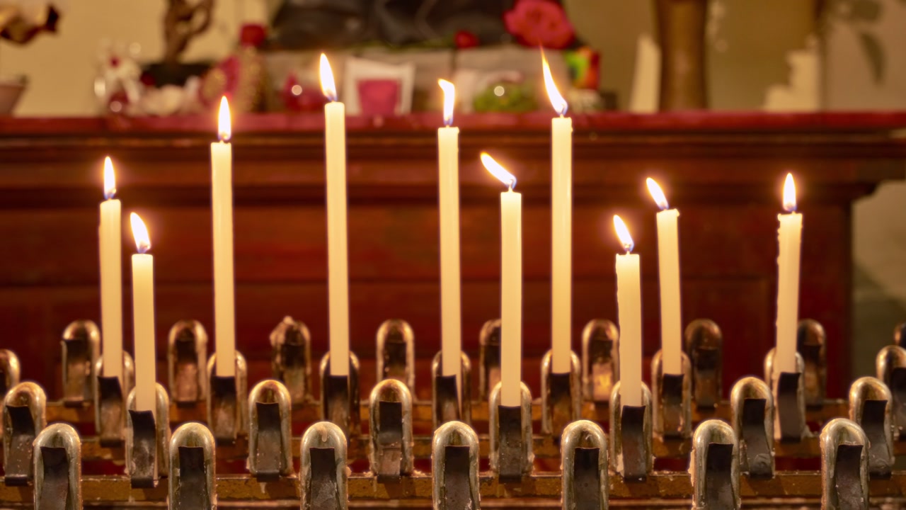 Burning votive candles in christian church by alter with flame and warm light. Faith and religion inside cathedral in European country. Altar candles lights for honor and prayer. Worship ceremony