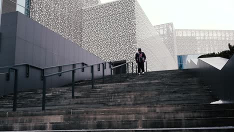 man walking up stairs in front of modern architecture