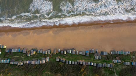 birds eye view tracking drone shot along beach huts at milford on sea in uk during sunset