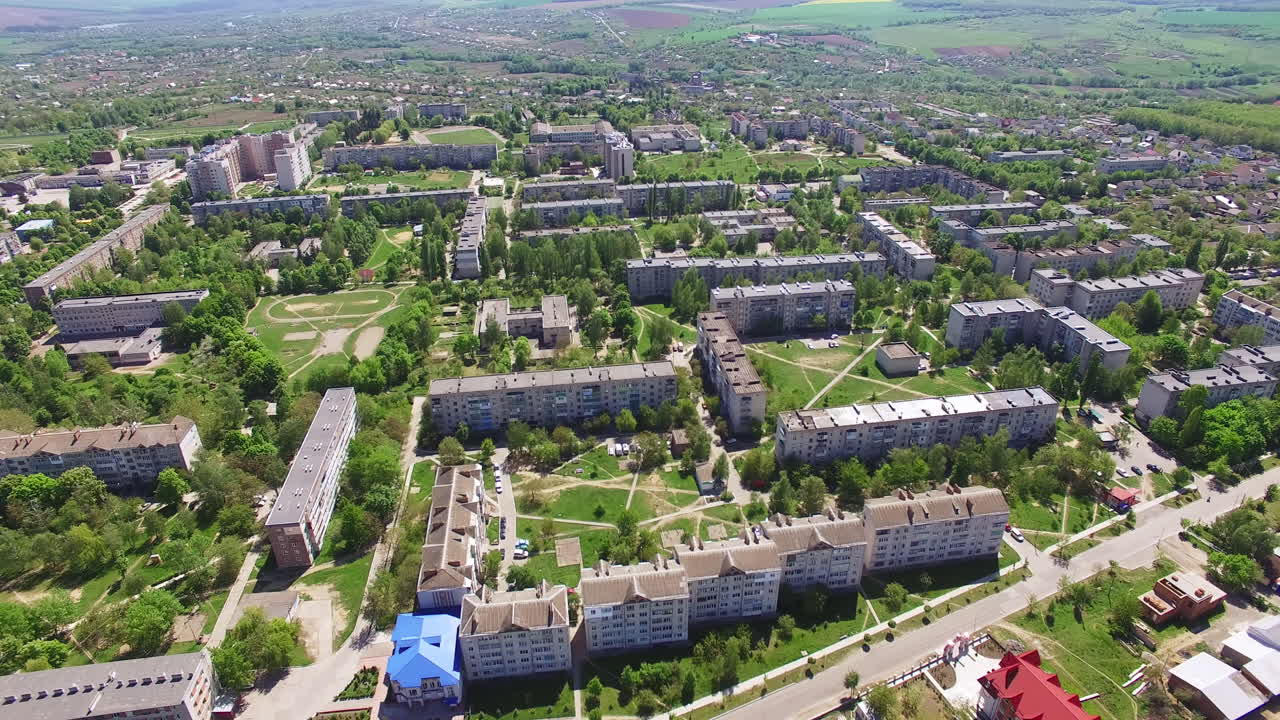 Multi-storied blocks of flats in the residential area. Lots of green trees growing among the houses. River at backdrop.
