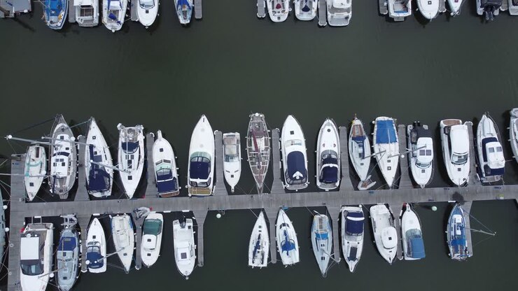 vista aérea de drones de arriba hacia abajo sobre lujosos veleros y yates amarrados en un puerto deportivo privado a la izquierda