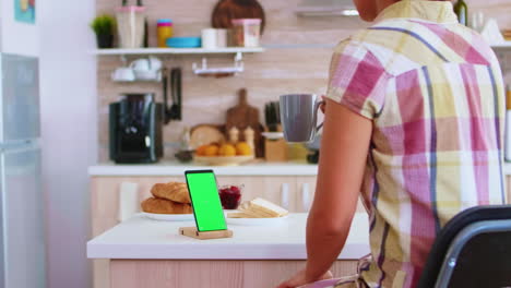 ama de casa mirando un teléfono móvil con pantalla verde
